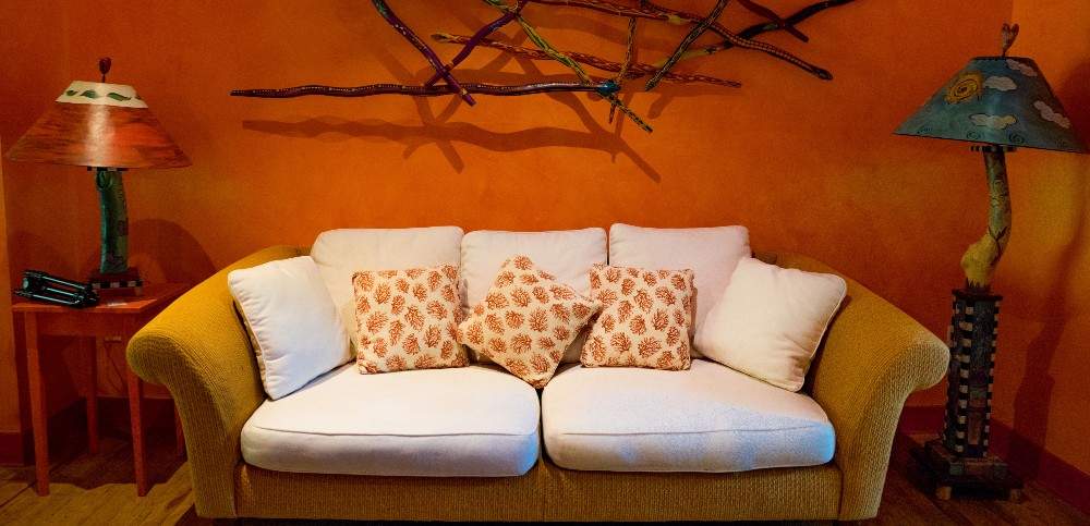 Room with orange walls and sofa with white cushions