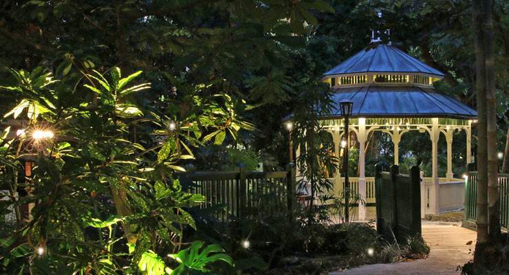 Gazeebo lit up at night in trees with lights